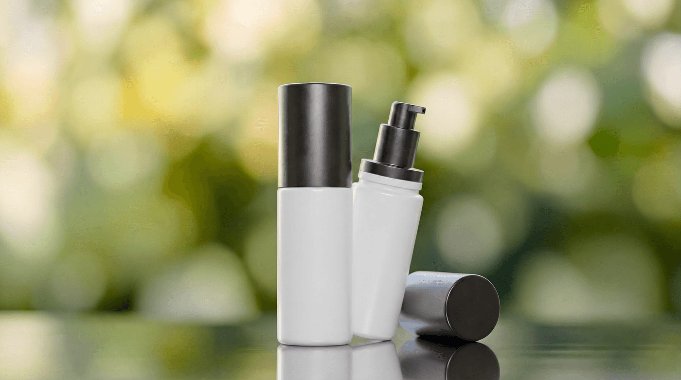White pump bottles with metal caps for topical application, soft green bokeh background